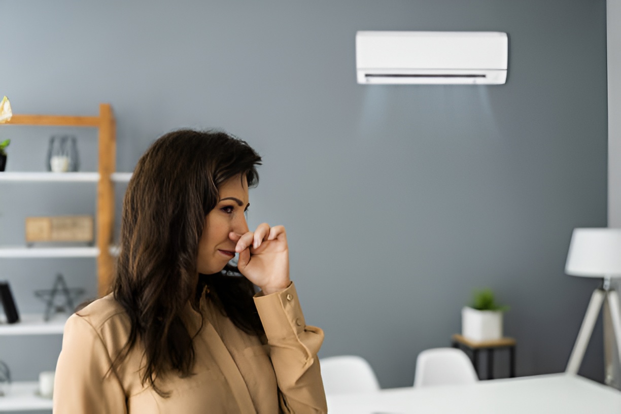 woman covering her nose while an air conditioning unit is blowing air